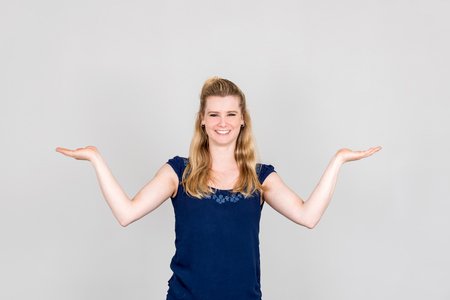 Studio shot of young woman presenting with both her hands palms upの写真素材