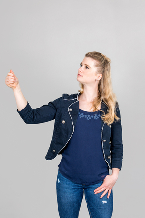 Studio shot of concentrated young woman pretending to hold something with her hand up in the air and looking at itの写真素材