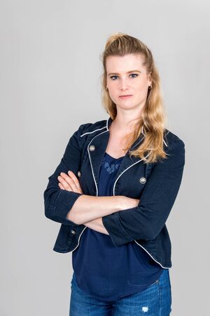 Studio shot of serious woman with folded arms looking into the camera in front of white backgroundの写真素材