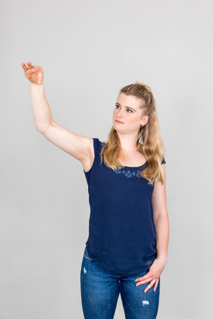 Studio shot of young woman pretending to hold something with her hand up in the airの写真素材