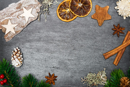 Top view of christmas decoration draped as frame on top of black shale as templateの写真素材