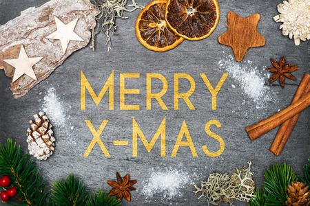 Top view of christmas decoration with snow on top of black shale with merry christmas writingの写真素材