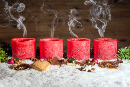 Four red blown out advent candles with fume in front of brown background as templateの写真素材