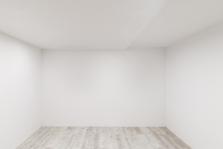 Empty room with whitewashed floating laminate flooring and newly painted white wall in backgroundの写真素材