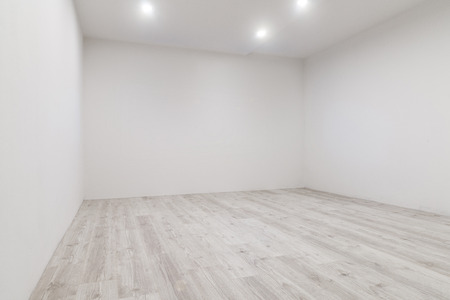 Empty room with whitewashed floating laminate flooring and newly painted white wall in backgroundの写真素材