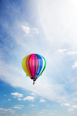 Colorful hot-air balloon flying high up in summer across blue skyの写真素材