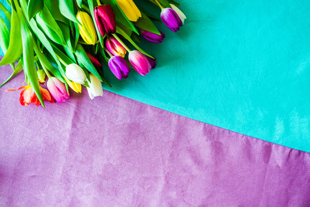 Happy Easter shot from above as flatlay with a bunch of tulips in front of colourful background symbolizing springの写真素材