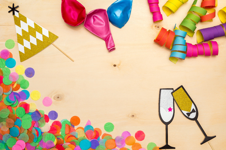 Colorful confetti, streamer and party hat as decoration lying on wooden background as flatlayの写真素材