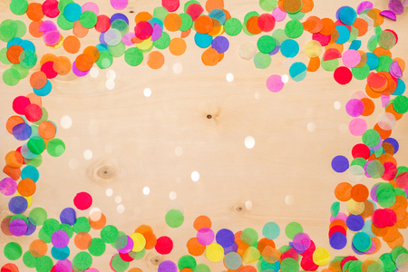 Colorful confetti lying on wooden background with blank copyspace as flatlayの写真素材
