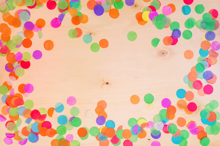 Colorful confetti lying on wooden background with blank copyspace as flatlayの写真素材