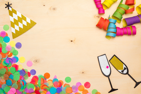 Colorful confetti, streamer and party hat as decoration lying on wooden background as flatlayの写真素材