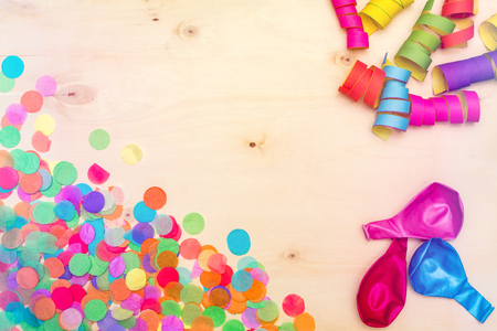 Colorful confetti and streamer as party decoration lying on wooden background with blank copyspace as flatlayの写真素材