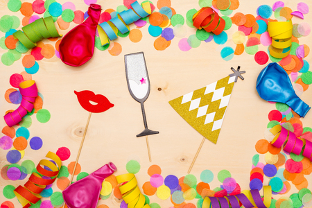 Colorful confetti, streamer and party hat as decoration lying on wooden background as flatlayの写真素材