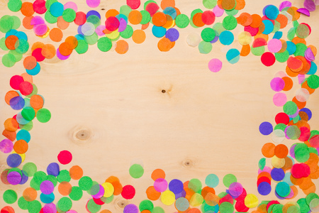 Colorful confetti lying on wooden background with blank copyspace as flatlayの写真素材