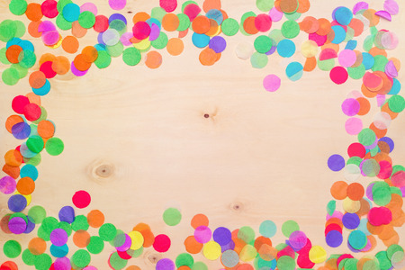 Colorful confetti lying on wooden background with blank copyspace as flatlayの写真素材