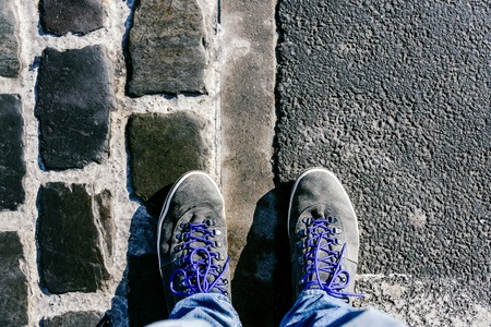 Reaching a crossroads having to decide about past, now and future symbolized by two feet and shoes...