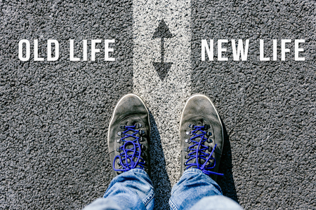 Reaching a crossroads having to choose between old life and new life and about future symbolized by two feet standing on two different colors with arrows on pathway from aboveの写真素材