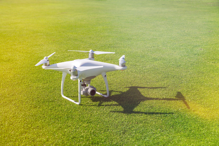 White professional quadcopter drone camera from above against green grass in backgroundの写真素材