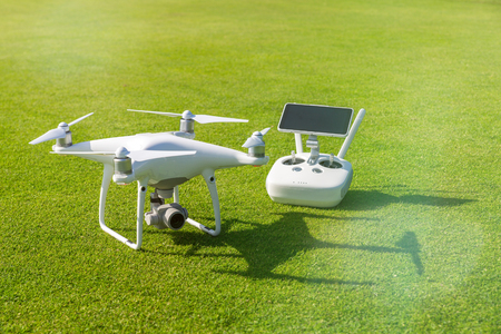 White professional quadcopter drone camera with remote control from above against green grass in backgroundの写真素材