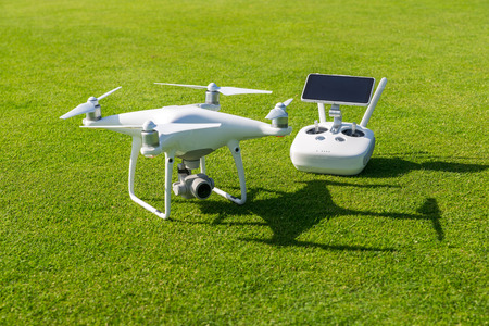 White professional quadcopter drone camera with remote control from above against green grass in backgroundの写真素材