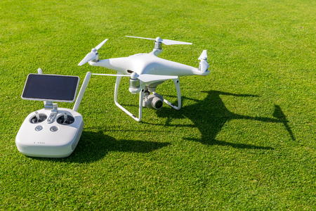 White professional quadcopter drone camera with remote control from above against green grass in backgroundの写真素材