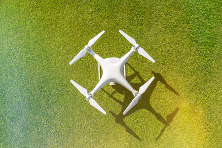 White professional quadcopter drone camera from above against green grass in backgroundの写真素材