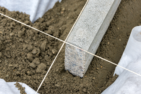 Setting edge restraints buy putting border curb stones in earth-moist concreteの写真素材