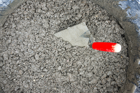 Bucket full of earth-moist concrete with red trowel for construction as close-upの写真素材