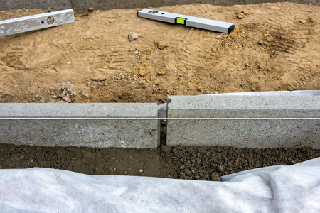 Setting edge restraints buy putting border curb stones in earth-moist concreteの写真素材