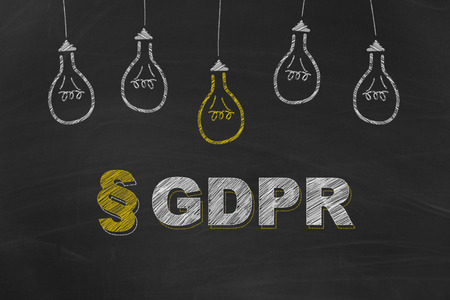 GDPR written with chalk and yellow and white light bulbs painted on dirty black chalkboardの写真素材
