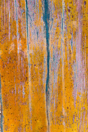 Closeup of colorful weathered old worn textured wall or floor in yellow, purple and blue as backgroundの写真素材