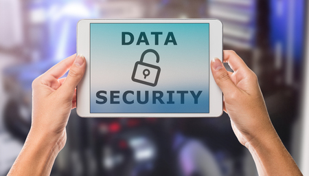 Data security written on tablet screen with hands holding the device up with server room in the backgroundの写真素材