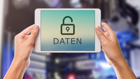 Data written in german on tablet screen with hands holding the device up with server room in the backgroundの写真素材