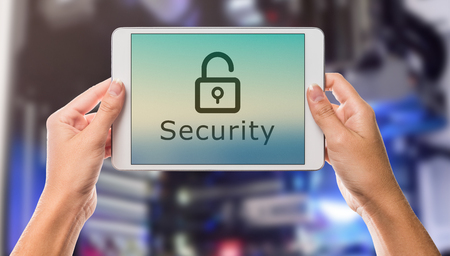 Security written on tablet screen with hands holding the device up with server room in the backgroundの写真素材