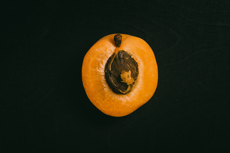 Cut peach with seed lying on black chalkboard in background with copy space from above as flat layの写真素材