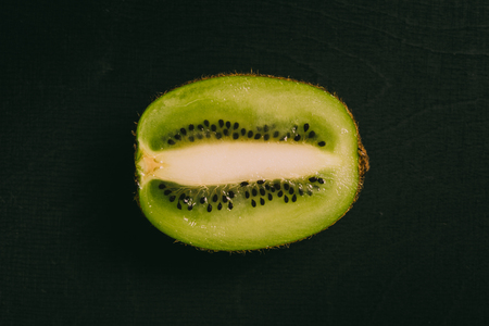 Cut kiwi fruit lying on black chalkboard in background with copy space from above as flat layの写真素材