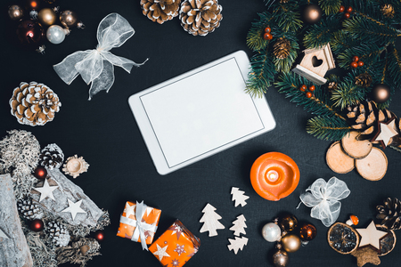 Christmas decoration and white tablet with copy space for happy new year message against black background as flatlayの写真素材