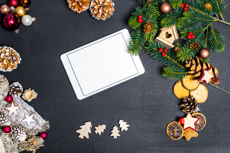 Christmas decoration and white tablet with copy space for happy new year message against black background as flatlayの写真素材