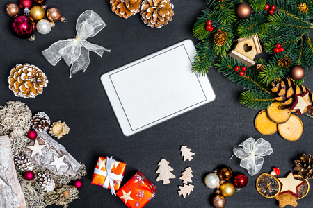 Christmas decoration and white tablet with copy space for happy new year message against black background as flatlayの写真素材