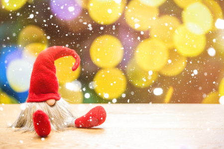 Red sitting christmas elf in falling snow with bokeh lights in background の写真素材