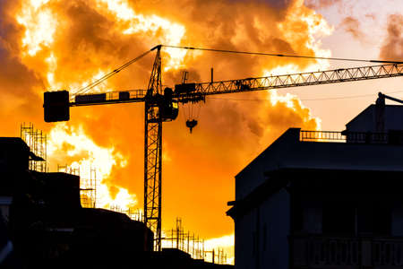 Silhouette of a construction crane against sunsetの写真素材