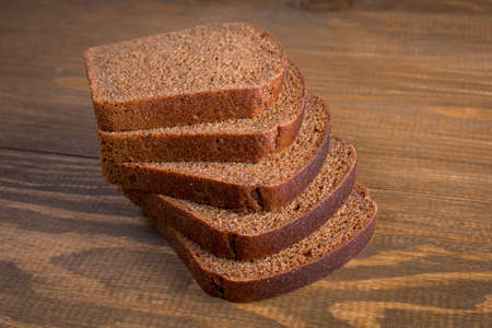 Sliced black rye bread on wooden background