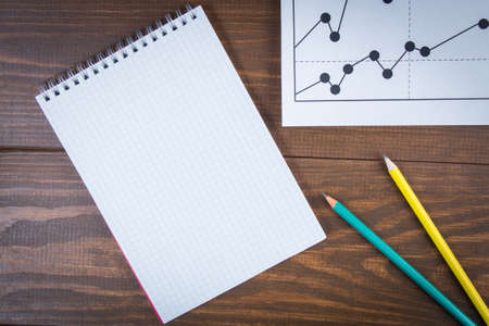 Business drawing graphics, pancils and white notepad on wooden backgroundの写真素材