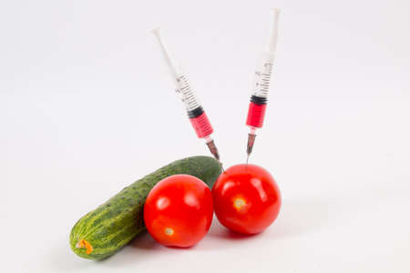 tomatoes and cucumber vegetables and syringe with nitrates. GMO food ingredient.の写真素材