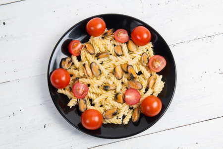 Italian pasta with mussels and tomatoes in a black plateの写真素材