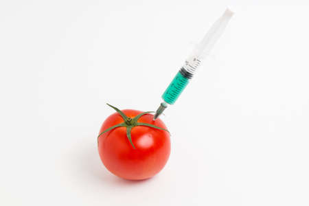Tomato and syringe with nitrates. GMO food ingredient concept.の写真素材