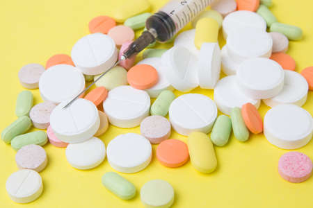 medicines syringe, pills, drugs and antibiotics on a yellow backgroundの写真素材