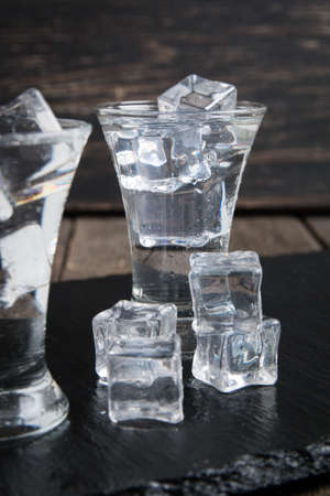 Vodka glass with ice on wooden table.の写真素材