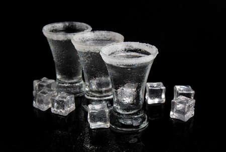 shot of tequila with salt and ice on black tableの写真素材