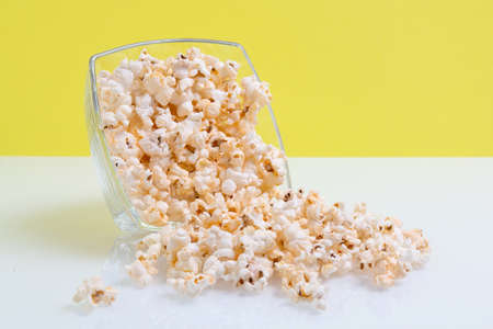 popcorn in a glass bowl on yellow backgroundの写真素材